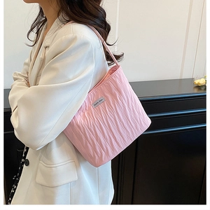 Detail shot of pink pleated tote bag featuring a metallic brand name plate on the fabric