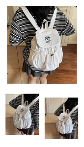 Close-up of white nylon backpack featuring flap design and MUT ING letter printing