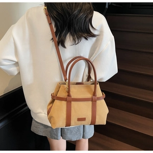 Détail d'un sac cabas en toile kaki et cuir marron porté en bandoulière sur l'épaule