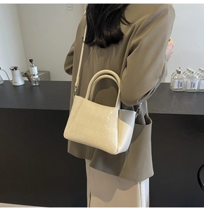 Detail shot of a beige quilted crossbody bag showing texture and silver metal clasp
