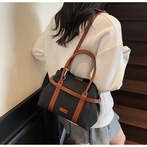 Détail d'un sac seau en toile avec finitions en cuir marron porté par un mannequin en extérieur
