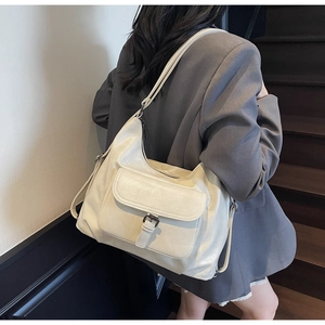 Detail of cream white faux leather tote bag with metal buckle and adjustable strap