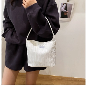 Detail of white quilted canvas tote bag with ruched texture and a small brand label