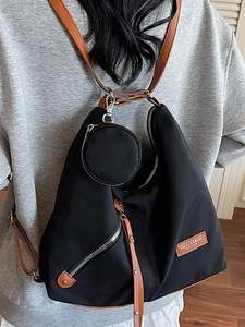 Fashionable black nylon backpack with brown leather straps and small coin purse attached
