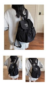 Close-up detail of black nylon backpack featuring white embroidery and drawstring closure