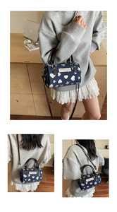 Dettaglio della borsa Boston blu navy con motivi a cuore e stelle e manici in pelle marrone