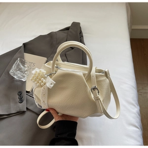 Detail of creamy white pleated handbag with pearl heart charm and lace ribbon decoration