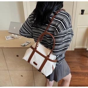Détail d'un sac cabas en toile et cuir marron porté par un mannequin au bureau