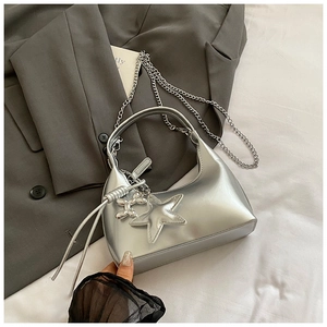 Detail of silver half-moon bag featuring a star pendant and metallic dog buckle