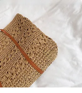 Close-up of crochet floral pattern and brown leather strap on straw shoulder bag