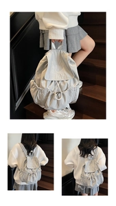 Detail of light grey drawstring backpack featuring NUT ING embroidery on the flap