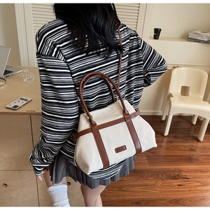 Grand sac seau en toile avec finitions en cuir marron porté par un mannequin en scène