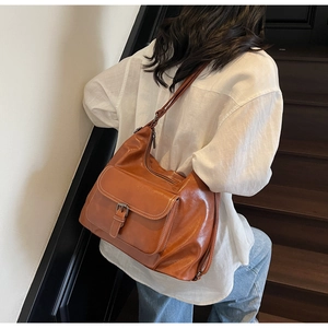 Close-up of brown large tote bag with white stitching and metal buckle on wooden stairs