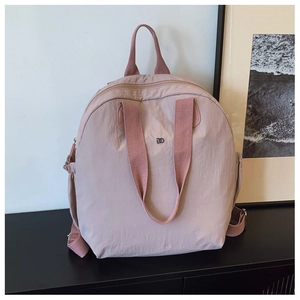 Detail of dusty rose puffer backpack showing lightweight nylon texture and metal logo