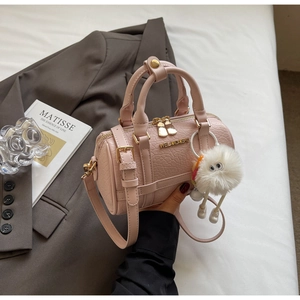 Pink boston bag with leather texture, gold hardware and a cute white plush monster charm