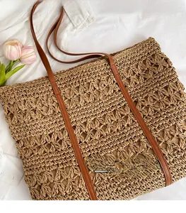 Close-up of handwoven straw tote bag featuring detailed hollow star patterns and leather straps