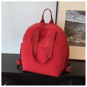 Close-up of red puffer backpack featuring durable straps and metallic logo detail