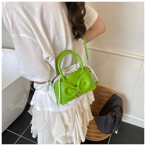 Modella che indossa una borsa verde con fiocco, fodera bianca e tracolla lunga