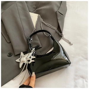Detail of black patent leather crescent bag with silver star and balloon dog charms