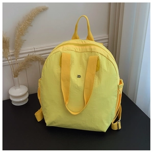 Detail view of water-resistant bright yellow puffer backpack with double handles and side pockets