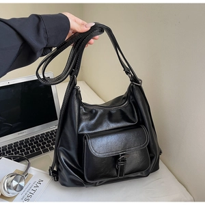 Detail of black soft leather tote bag with white contrast stitching and buckle pocket