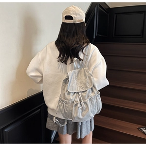 Rear view of a model wearing the light grey canvas backpack with white Muting embroidery