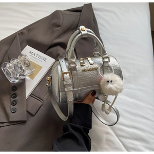 Detail of silver metallic textured Boston bag with gold zippers and plush charm decoration