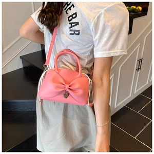 Dettaglio della borsa rosa con fiocco, ciondolo a cuore e manico in pelle in stile casual