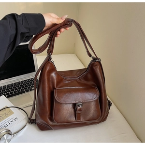 Detailed close-up of brown oiled leather texture and buckle hardware on a tote bag
