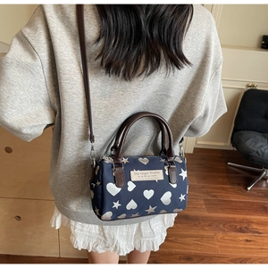 Dettaglio della mini borsa Boston blu navy con cuori indossata da una modella