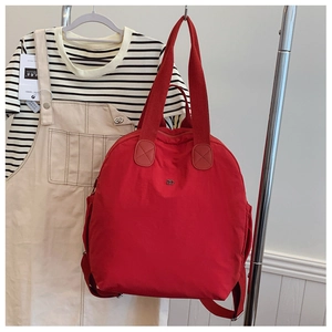 Detail of red nylon puffer backpack with metal logo and side pockets for storage