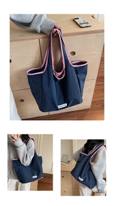 Detail showing deep blue tote bag with pink trim and brand label in home setting