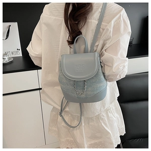 Detail of light blue mini backpack featuring tweed fabric and silver chain decoration