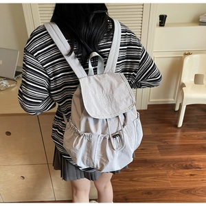 Detailed back view of a light gray nylon backpack showing the Nutin logo and side pocket