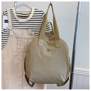Khaki puffer backpack with CD logo displayed on clothes hanger with casual outfit
