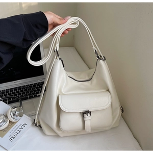 Detailed view of cream tote bag with leather buckle pocket and adjustable shoulder strap