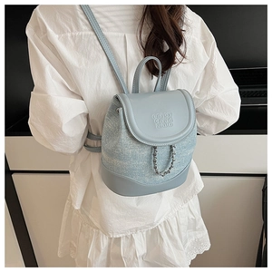 Detail view of mini blue backpack featuring embossed flap and silver chain accents