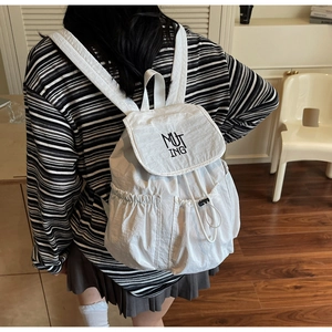 Close-up of white nylon drawstring backpack with black MUT ING embroidery and side pocket