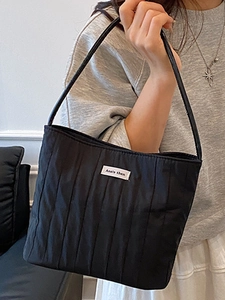 Minimalist black quilted tote bag with vertical stripes and stylish shoulder handles
