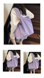 Detail of a large purple canvas tote bag with a minimalist logo tag and gray piping trim