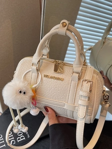 Elegant cream white pillow bag with animal texture, gold logo, and plush monster charm