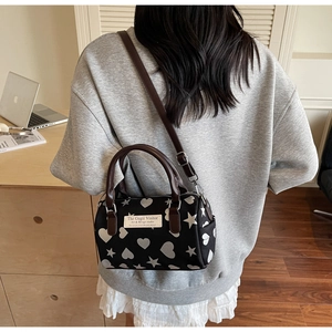Dettaglio borsa Boston da donna con stampe bianche di cuori e stelle su materiale nero
