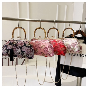 Detail of embroidered floral handbags with bamboo handles and elegant silk tassels
