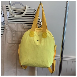 Detail view of yellow lightweight puffy backpack with side pockets and top handles