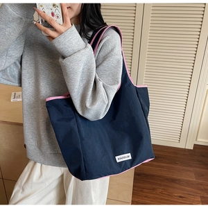 Modern navy nylon tote bag with pink trim worn by a model in a minimalist room