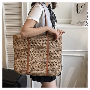 Detail shot of the hollow-out woven straw tote bag with brown synthetic leather straps