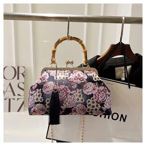 Detail of vintage floral embroidery on black silk bag with bamboo handle and gold frame