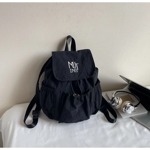 Detail shot of black nylon backpack with MUTING logo and side drawstring pockets