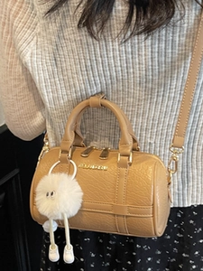 Elegant caramel pillow bag with top handles, crossbody strap, and fun plush charm