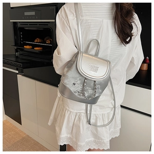Detail of silver fashion backpack with metallic leather and chain strap on model